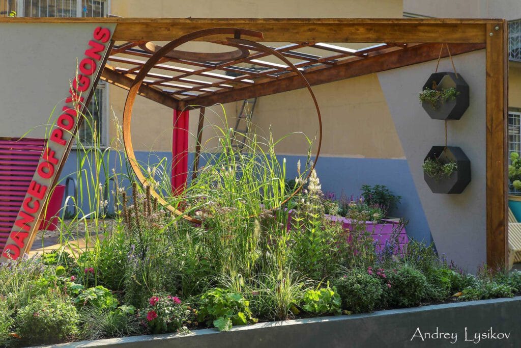 Puutarha, jonka taustalla on rakenne. Kuvassa on harmaa ja ruskea väri. Mukana myös rakennus, huonekasvi, ulkona.