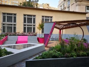 Värikäs puutarha rakennuksen edessä. Kuvassa on harmaa ja musta väri. Huoneessa on myös ulkona, ikkuna, taivas.