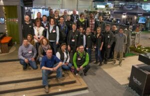 Ryhmä ihmisiä poseeraa valokuvassa. Kuvassa on harmaa ja musta ja ruskea värit. Näyttää 27 henkilöä. Sisältää myös vaatteita, henkilöä, jalkineita.