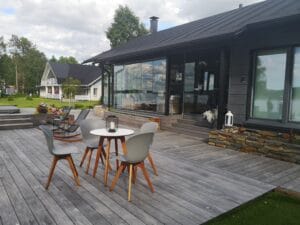 Pöytä ja tuolit kannella. Kuvassa on harmaa ja valkoinen väri. Sisältää puun, ruokapöydän ja tuolin. Huoneessa on myös ulkona, taivas, huonekalut.