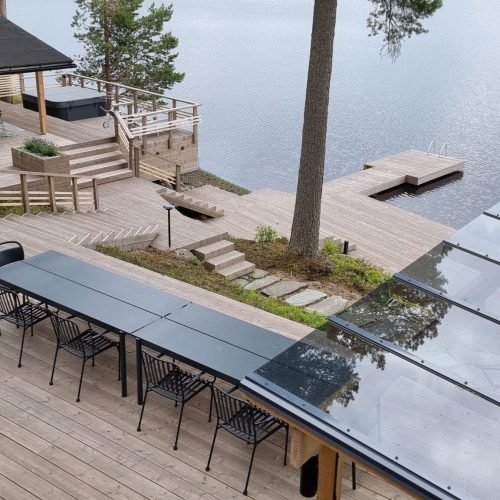 Kansi, jossa on uima-allas ja tuoleja. Kuvassa on harmaa ja valkoinen väri. Sisältää tuolin, kasvin ja penkin. Huoneessa on myös ulkona, järvi, vesi.