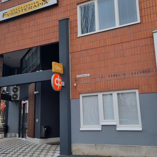 Rakennus, jossa on kyltti. Kuvassa on harmaa ja ruskea väri. Sisältää auton ja ikkunan. Sisältää myös tekstin, ulkona, taivaan.