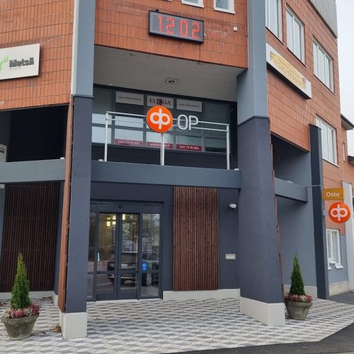 Rakennus, jonka edessä on kyltti. Kuvassa on harmaa ja valkoinen väri. Sisältää myös ulkona, taivaan, tekstin.