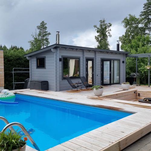 Uima-allas, jonka taustalla on talo. Kuvassa on harmaa ja valkoinen väri. Sisältää puun, palmun ja uima-altaan. Mukana myös taivas, ulkona, rakennus.