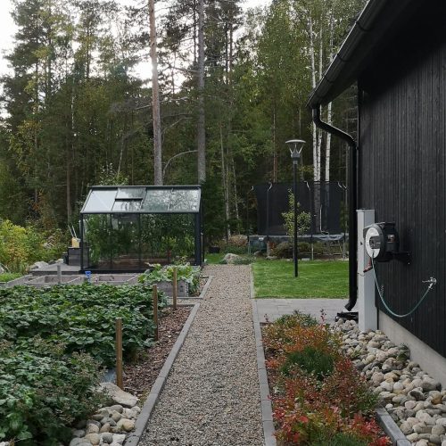 Pieni puutarha, jossa on kyltti. Kuvassa on harmaa ja musta väri. Huoneessa on myös ulkona, taivas, maisemointi.