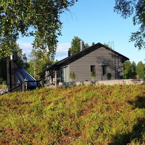 Talo, jonka edessä on lampi. Kuvassa on mustat ja keltaiset värit. Mukana myös ulkona, taivas, kasvi.