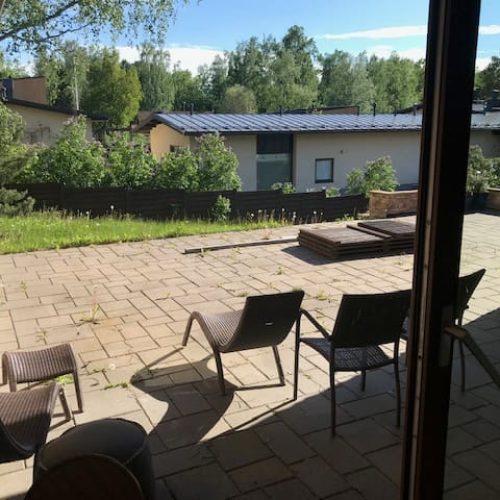 Patio, jossa on tuoleja ja pöytä. Kuvassa on mustia värejä. Huoneessa on myös ulkona, puu, huonekalut.