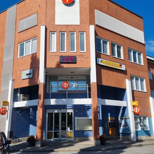 Rakennus, jossa on kyltti. Kuvassa on sininen ja harmaa väri. Huoneessa on myös ulkona, taivas, auto.