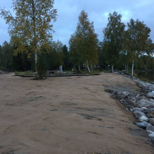 Hiekkatie, jonka sivussa on puita. Kuvassa on harmaa ja musta väri. Mukana myös ulkona, taivas, pilvi.