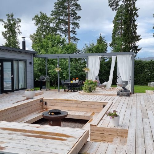 Takapiha, jossa on suihkulähde. Kuvassa on valkoinen ja harmaa väri. Sisältää palmuja, kasveja ja puita. Mukana myös taivas, rakennus, ulkona.