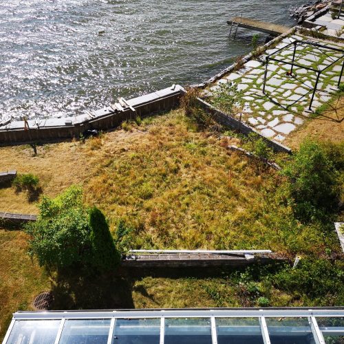 Juna kulkee joen varrella. Kuvassa on harmaa ja musta väri. Mukana myös ulkona, kasvi, ruoho.