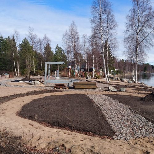 Rakennustyömaa, jossa on järvi ja puita. Kuvassa on harmaat värit. Mukana myös ulkona, maa, taivas.