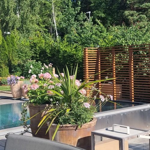 Uima-allas, jossa on kansi ja tuoleja. Kuvassa on vihreä ja harmaa väri. Sisältää myös ulkona, rakennuksen, puun.