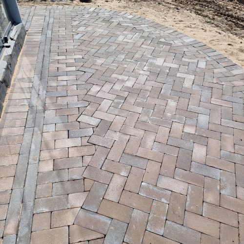 Tiilinen kävelytie, jossa on tiilipolku. Kuvassa on harmaat värit. Mukana myös maa-, ulko-, mukulakivi.