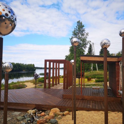 Puurakenne, jonka ympärillä on aita. Kuvassa on valkoinen ja ruskea väri. Mukana myös ulkona, taivas, pilvi.