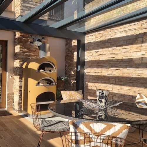 Patio, jossa on pöytä ja tuolit. Kuvassa on ruskea ja harmaa väri. Huoneessa on myös huonekalut, sohvapöytä, keittiö ja ruokapöytä.