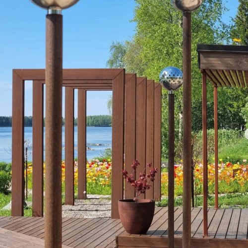 Puinen kansi, jossa on kaide ja vesistö taustalla. Kuvassa on ruskeat värit. Mukana myös ulkona, taivas, kasvi.