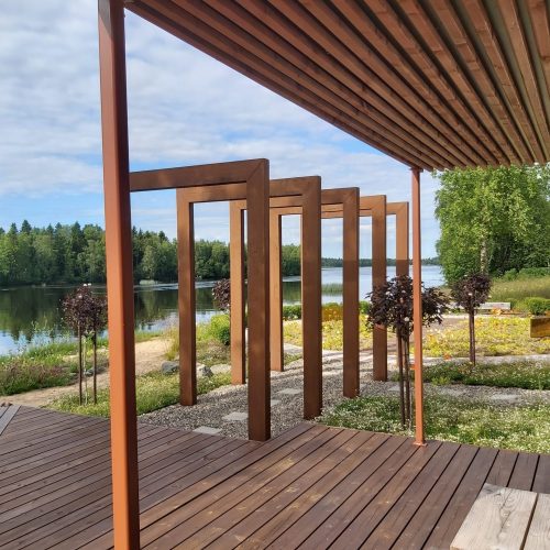 Puukansi, jossa on katettu alue. Kuvassa on ruskeat värit. Mukana myös ulkona, taivas, rakennus.