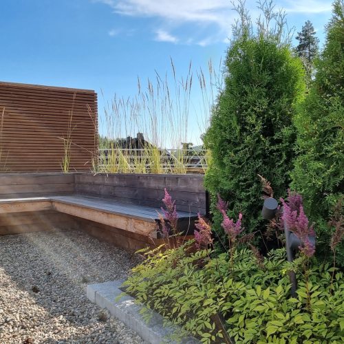 Takapiha, jossa on puita ja rakennus. Kuvassa on harmaa ja vihreä väri. Mukana myös ulkona, taivas, pilvi.