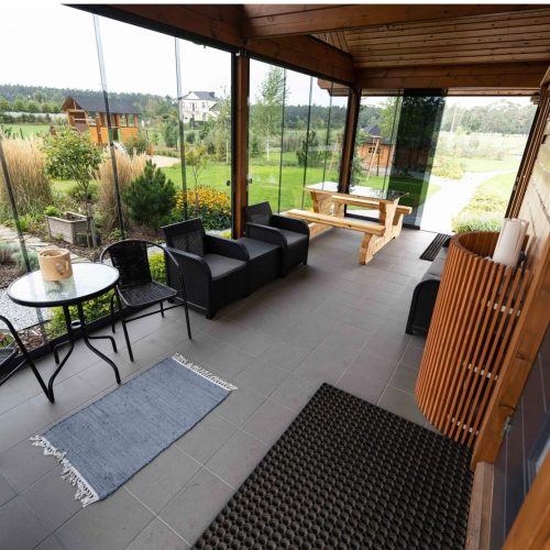 Patio, jossa on pöytä ja tuolit. Kuvassa on harmaa ja ruskea sekä musta väri. Sisältää istuimet ja tuolin. Sisältää myös rakennuksen, huonekalut, kasvin.