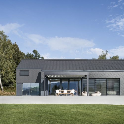 Talo, jossa on nurmikko ja puita. Kuvassa on harmaat värit. Sisältää myös ulkona, ruohoa, pilviä.