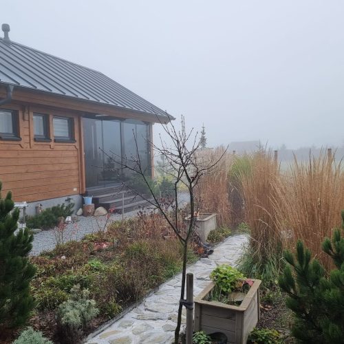 Talo, jossa on suuri piha. Kuvassa on valkoinen ja harmaa väri. Sisältää asuntolan ikkunan ja talon. Mukana myös ulkona, kasvi, taivas.