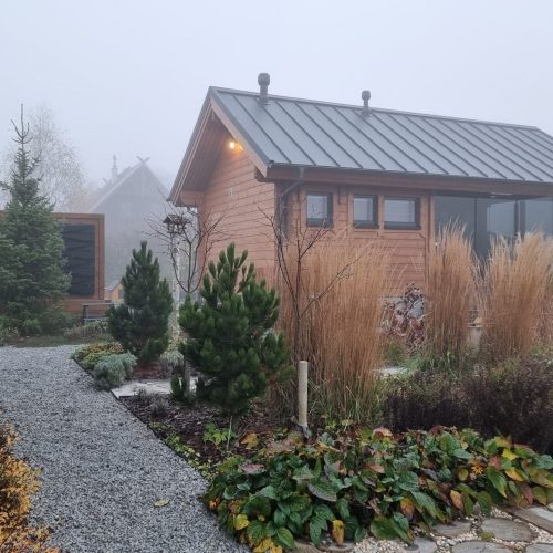 Talo, jossa on sora-ajotie. Kuvassa on harmaa ja valkoinen väri. Sisältää puun, kasvin ja talon. Huoneessa on myös ulkona, taivas, ikkuna.