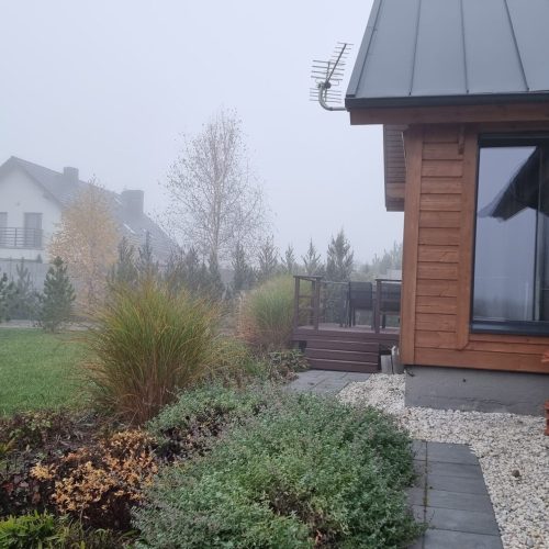 Talo, jossa on piha ja aita. Kuvassa on harmaa ja valkoinen väri. Sisältää puun, talon ja ikkunan. Mukana myös ulkona, kasvi, taivas.