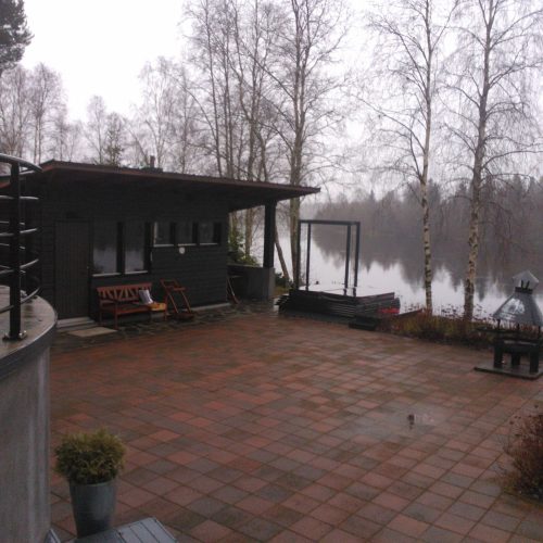 Tiilipatio, jossa on tiilipatio ja katettu patio, jossa on puita. Kuvassa on valkoinen ja harmaa sekä musta värit. Mukana myös ulkona, taivas, kasvi.