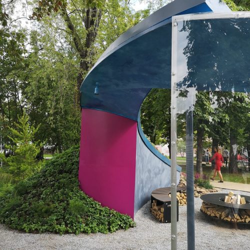 Teltta ulkona, puita takana. Kuvassa on harmaat värit. Mukana myös ulkona, varjossa, kasvina.