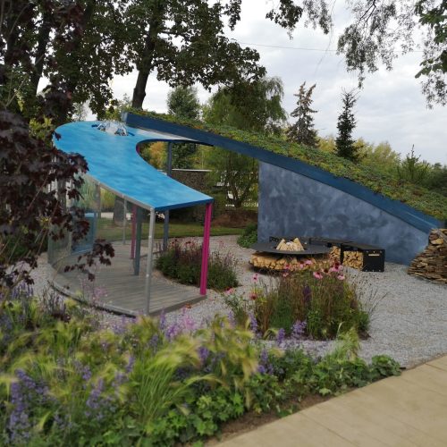 Pieni sininen teltta puutarhassa. Kuvassa on harmaa ja musta väri. Mukana myös ulkona, kasvi, puu.