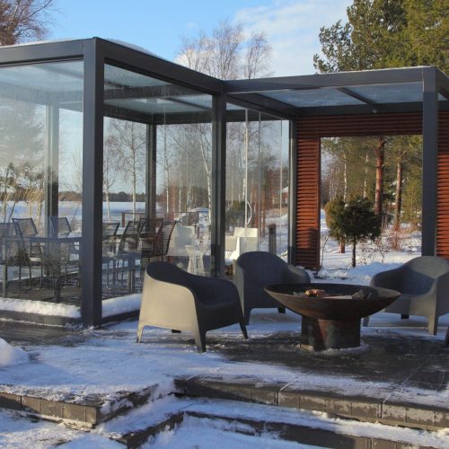 Katettu patio, jossa on pöytä ja tuolit lumessa. Kuvassa on harmaat värit. Sisältää istuimet ja tuolin. Mukana myös ulkona, puu, talvi.