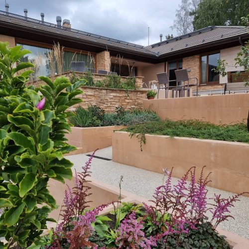 Puutarha talon edessä. Sisältää puuta ja rakennusta. Mukana myös ulkona, taivas, pilvi.