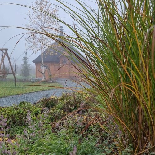 Rakennus aidan takana. Kuvassa on harmaat värit. Mukana myös ulkona, taivas, kenttä.